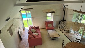 Un espacio habitable amplio con un sofá rojo, una mesa de centro y una mesa de comedor con sillas. Una ventana grande ofrece vistas del exterior.