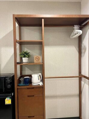 Ein Holzschrank mit mehreren Einlegeböden, einer kleinen Pflanze, einem Wasserkocher und einer Tasse.