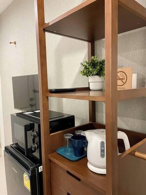 Eine Küchenzeile mit Kaffeemaschine, Wasserkocher und einer kleinen Pflanze auf einem Regal.