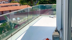 Een balkon met vrij uitzicht op een berg, palmbomen en een gebouw met rode dakpannen.