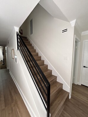 Eine Treppe mit Holzboden und einem schwarzen Geländer, die zu einer weißen Tür führt.
