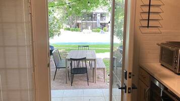 A kitchen with a microwave, a dining area with a table and chairs, and a view of a residential area through a glass door.