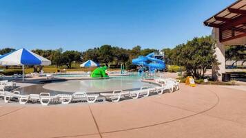 Un parc aquatique avec une piscine, des toboggans et des chaises longues.