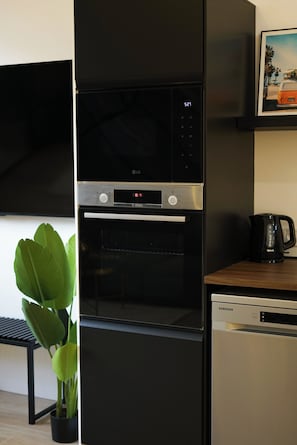 A kitchen with a black refrigerator, oven, and dishwasher, a black coffee maker, and a potted plant.
