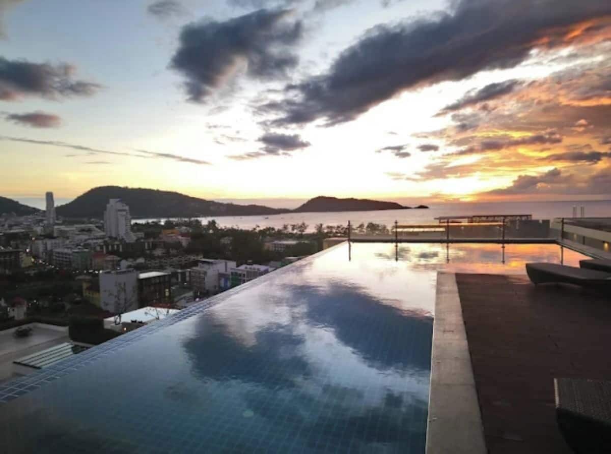 An infinity pool with a cityscape and mountains in the background.