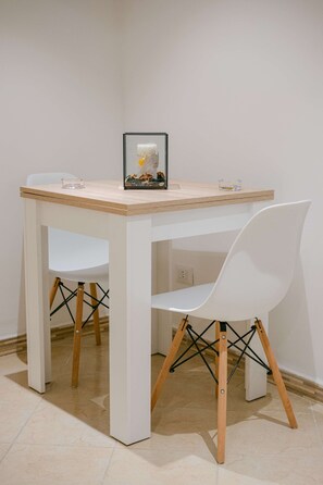 Ein weißer Tisch mit einer Glasplatte, ein weißer Stuhl mit Holzbeinen und ein gerahmtes Bild darauf.