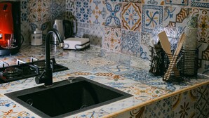 Una cucina con lavello nero, fornello a gas e macchina da caffè.