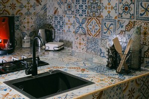 Eine Küche mit einer schwarzen Spüle, einem Gasherd und einer Kaffeemaschine.
