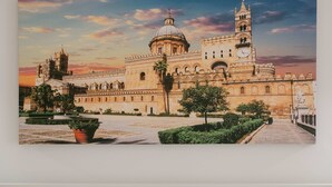 Un grande edificio storico con una cupola imponente e una torre dell'orologio, circondato da un ampio cortile con una fontana centrale e vegetazione.