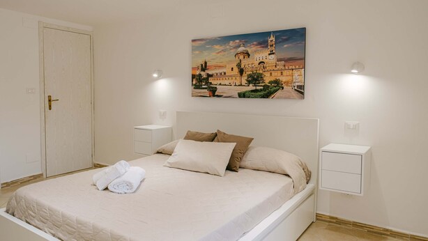 Una camera da letto con un letto, un quadro, comodini e una porta.