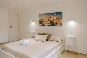 Un dormitorio con cama, un cuadro, mesitas de noche y una puerta.