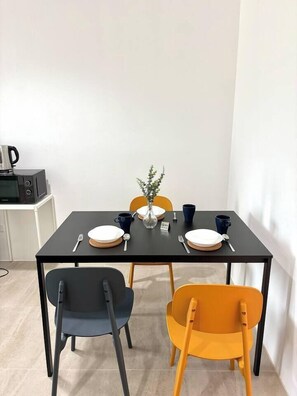 A dining table with four chairs, a vase with a plant, and a microwave in the background. - 1minBTS-Wifi500Mbs-Workplace>NETFLIX/Central (Khlong Toei)