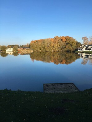 A calm lake with a dock, surrounded by trees and a house. - Luxury Lakeside Fishing Lodge Tattershall Lakes (Tattershall)