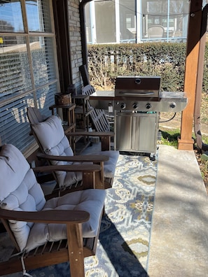Eine Terrasse mit Grill, Sitzgelegenheiten im Freien und Blick auf ein Haus.