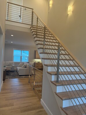A staircase with wooden steps and metal railings, leading to an upper level. - Spacious Custom New 5-bedroom house, Sleeps 12, Private Dock, Elevator (Englewood)