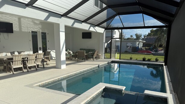 Una piscina con solárium de baldosas, mobiliario exterior y una zona cubierta con vistas al vecindario.