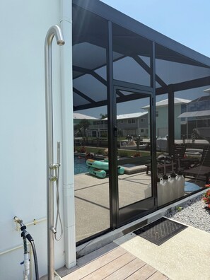 A modern outdoor pool area with a glass enclosure, a hose for water access, and a view of a residential neighborhood. - Spacious Custom New 5-bedroom house, Sleeps 12, Private Dock, Elevator (Englewood)