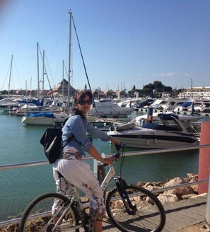 Eine Person auf einem Fahrrad mit Blick auf eine Marina und Boote.