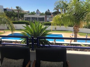 Área de piscina com vista para edifícios e palmeiras.