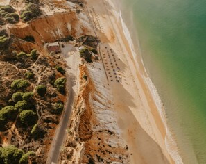 Vue aérienne d’une zone côtière avec une route, une plage et de la végétation.