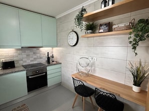 A modern kitchen with teal cabinets, a wooden dining table, and black chairs. - Cozy Apartment in Vilamoura Marina with Pool & Balcony (vilamoura)