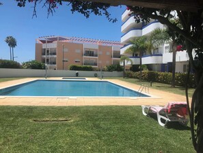 Une piscine à l’eau d’un bleu limpide, entourée d’une pelouse bien entretenue et, au fond, d’un bâtiment doté de balcons.