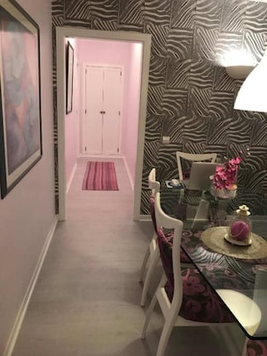 A dining area with a zebra-patterned wall, a glass table, white chairs, and a pink rug. - Cozy Apartment in Vilamoura Marina with Pool & Balcony (vilamoura)