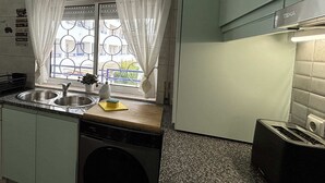 Pieni, käytännöllinen keittiö, jossa on pyykinpesukone, pesuallas ja leivänpaahdin.
