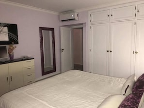 A bedroom with a bed, a wardrobe, a mirror, and an air conditioning unit. - Cozy Apartment in Vilamoura Marina with Pool & Balcony (vilamoura)