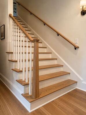 A wooden staircase with white balusters and a handrail, leading to a landing. - Collins River Farmhouse (McMinnville)