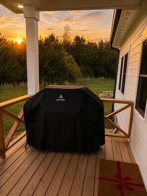A covered barbecue grill on a wooden deck with a view of a house and trees. - Collins River Farmhouse (McMinnville)