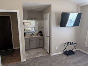 A bedroom with a bed, a dresser, a mirror, a TV, and a small seating area. - Beautiful 2-bedroom townhome on golf course in Mesa (mesa)