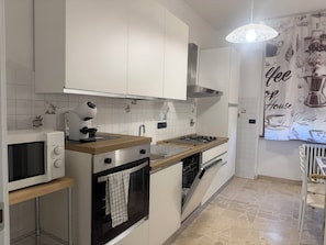 A modern kitchen with white cabinets, a microwave, an oven, a gas stove, and a dishwasher. - IRIS VIOLA Apartment in the heart of Bagno a Ripoli just minutes from the center (Bagno A Ripoli)