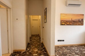 A hallway with a patterned floor, a door at the end, and a wall-mounted air conditioner. - IRIS VIOLA Apartment in the heart of Bagno a Ripoli just minutes from the center (Bagno A Ripoli)