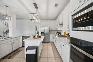 A modern kitchen with white cabinetry, stainless steel appliances, and pendant lighting. - Modern and Relaxing Home | Frisco Prime Location (Frisco)