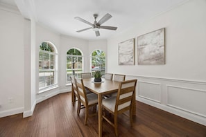 A dining room with a wooden table, chairs, a ceiling fan, and large windows with arched tops. - Modern and Relaxing Home | Frisco Prime Location (Frisco)