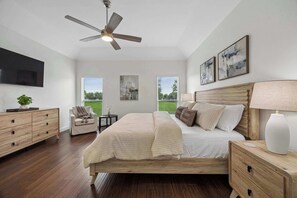 A bedroom with a bed, bedside tables, a ceiling fan, a TV, and artwork on the walls. - Modern and Relaxing Home | Frisco Prime Location (Frisco)