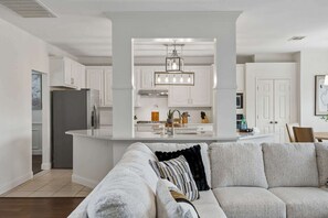 A modern kitchen with white cabinetry, a central island, and a hanging light fixture. - Modern and Relaxing Home | Frisco Prime Location (Frisco)