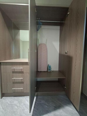 Ein begehbarer Kleiderschrank mit Holztüren, einer Kleiderstange und einem Regal.