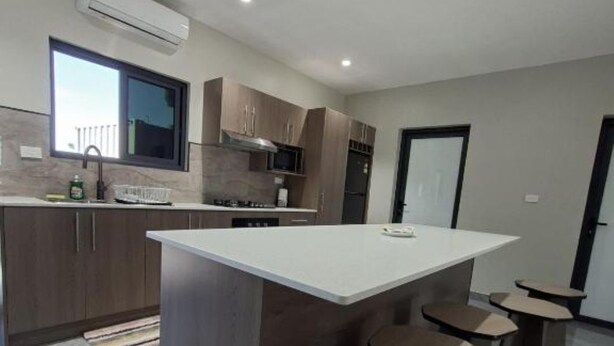 A modern kitchen with a central island, built-in appliances, and a window. - Pacific Sunrise Apartments #4 (Western Division)
