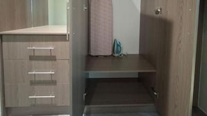 A walk-in closet with wooden doors, a hanging rod, and a shelf. - Pacific Sunrise Apartments #4 (Western Division)