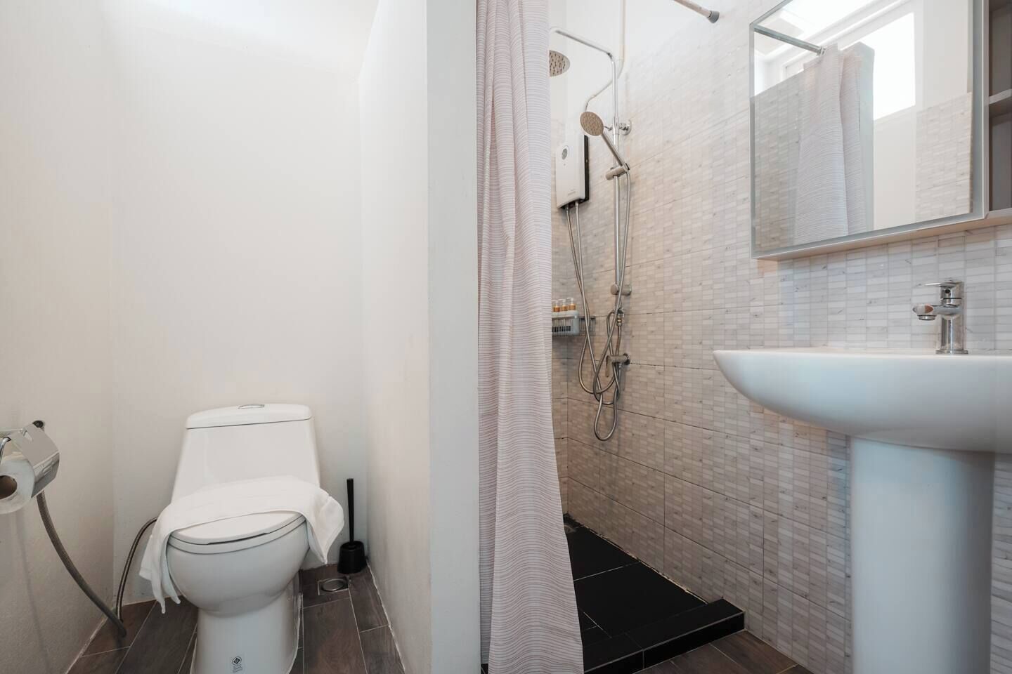 A bathroom with a toilet, shower, and sink.