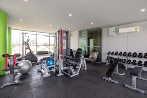 Ein Fitnessraum mit Trainingsgeräten, Bänken und einer Wand voller Kurzhanteln.
