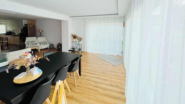 Un soggiorno moderno con zona pranzo, cucina e ampie finestre.