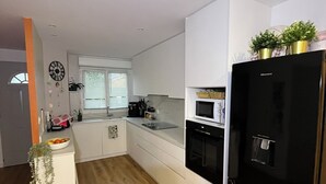 Una cucina moderna con mobili bianchi, un frigorifero nero e un pavimento in legno.
