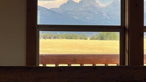 Ein Fenster mit Blick auf ein Gebirge und ein Feld.