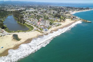 Luftaufnahme einer Küstenstadt mit Strand, Fluss und Wohngebieten.