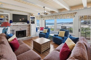 Ein Wohnzimmer mit Kamin, blauen Sofas, einem Holztisch und einem Fernseher.