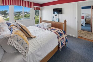 Ein Schlafzimmer mit Bett, einem an der Wand befestigten Fernseher und Blick ins Freie.