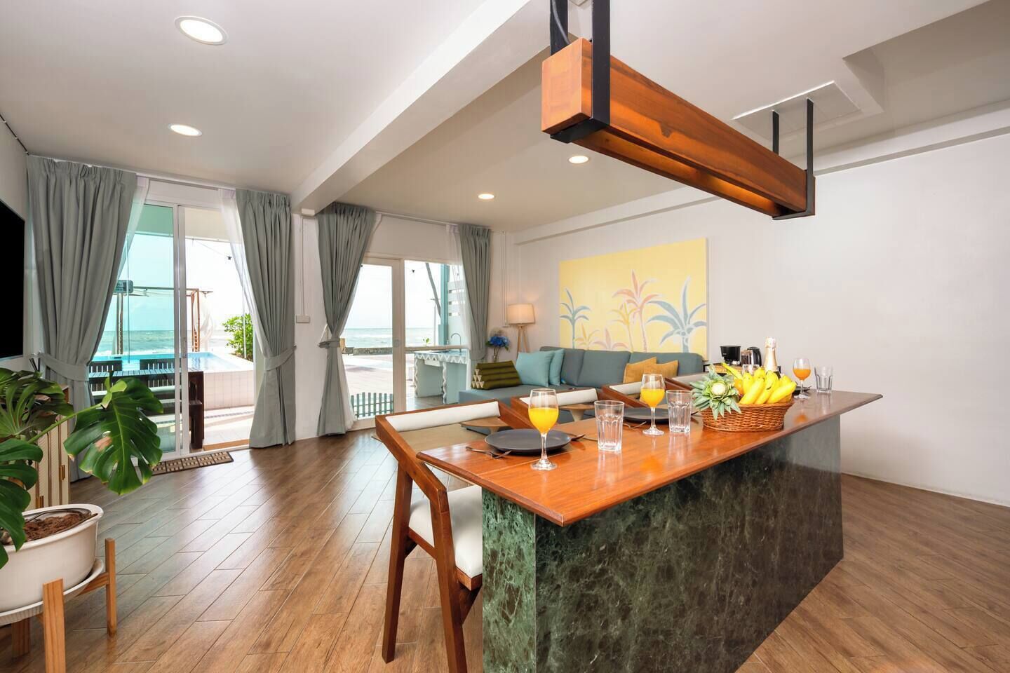 A modern kitchen with a wooden island, a dining area, and a view of the ocean.